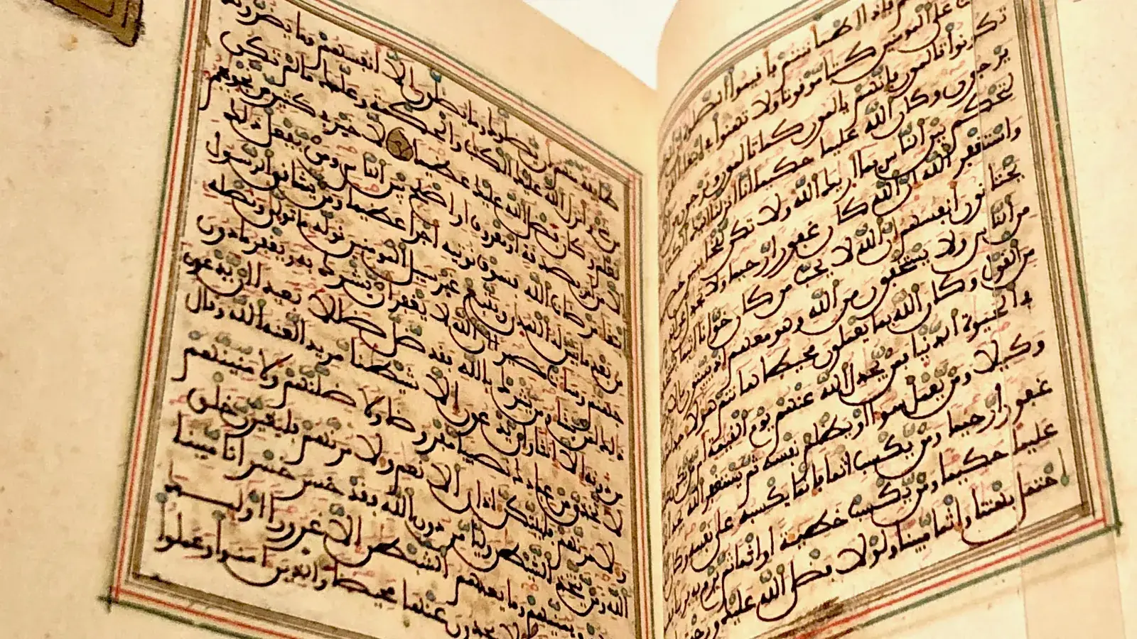 Beleuchtete arabische Manuskripte aufgeschlagen auf einem Holzschreibtisch, Kalligraphie in Gold und schwarzer Tinte, mittelalterliche islamische Bibliothek Al-Quaraouiyine